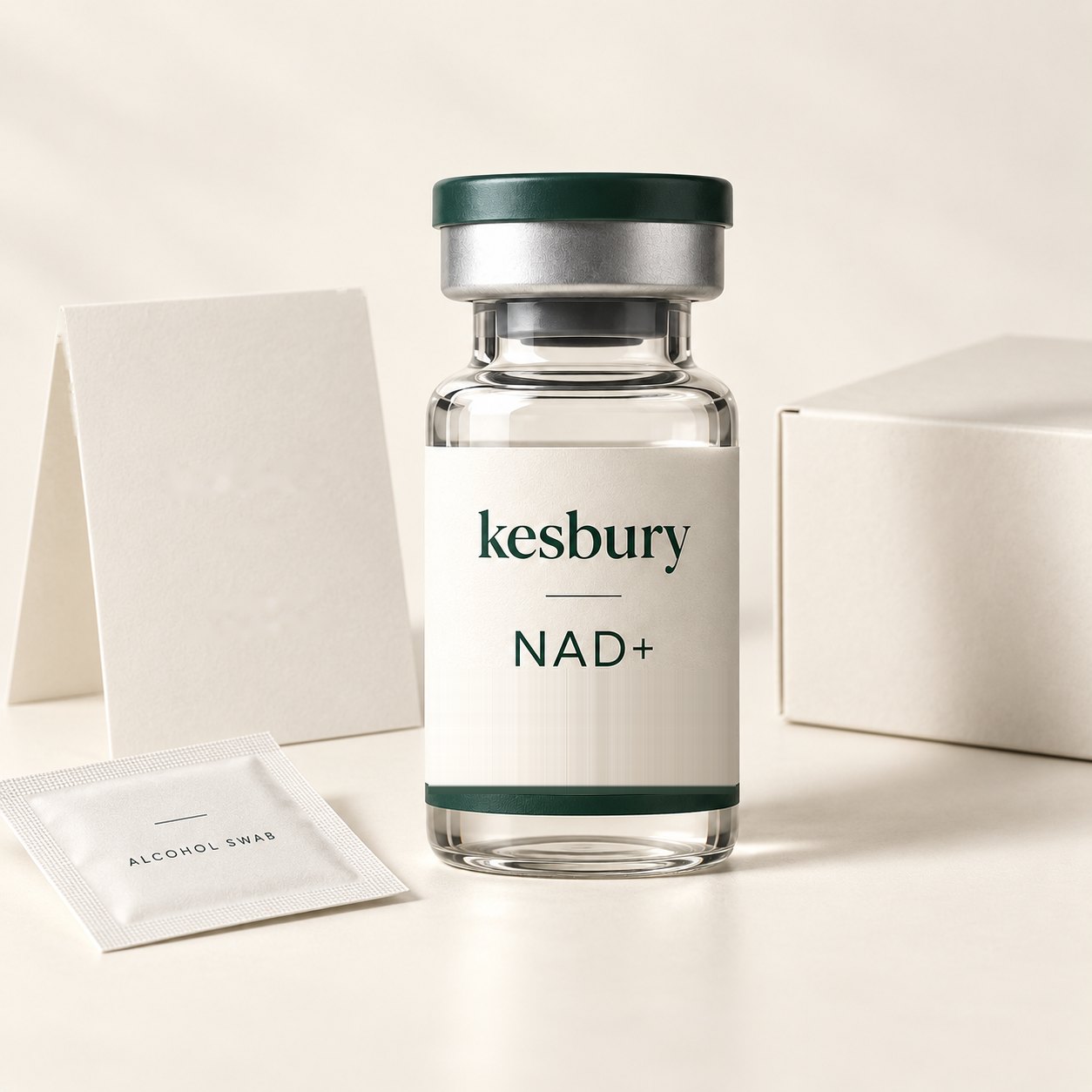 Illustration: a kit concept: a labelled Kesbury NAD+ vial beside a plain white box, a blank folded card, and an alcohol swab sachet.